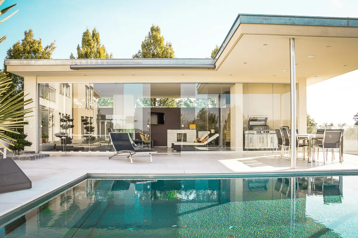 A glass-walled villa beside a long swimming pool
